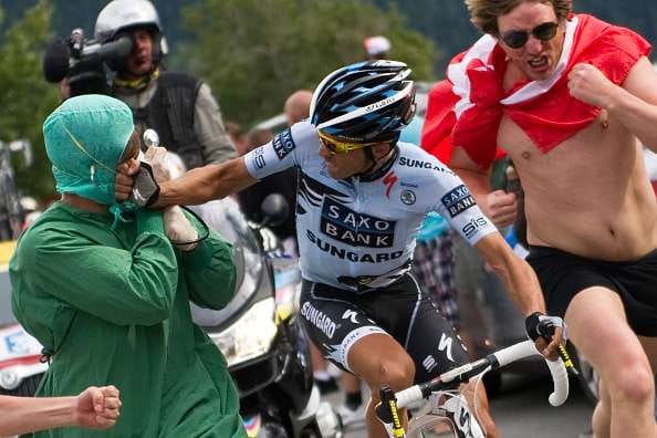 Alberto Contador (C) punches a fan dressed up as a doctor as he climbs Alpe d